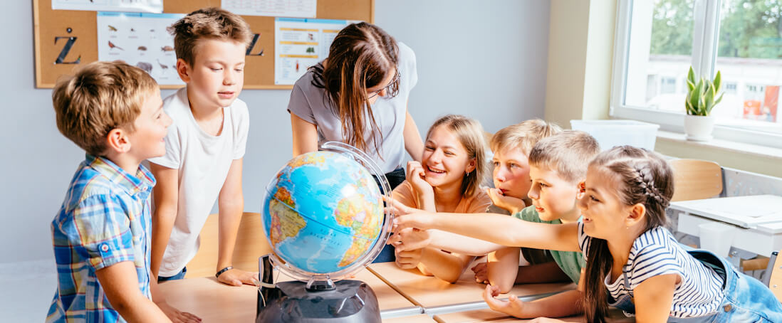 Teacher and children interacting with a world globe